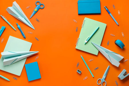 Composition with stationery supplies and paper planes on orange backgroundの写真素材