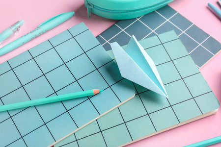 Composition with stationery supplies and paper plane on pink background