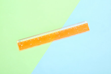 Orange plastic ruler on color backgroundの写真素材