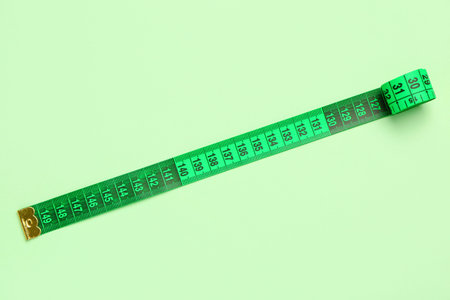 Green measuring tape on color background