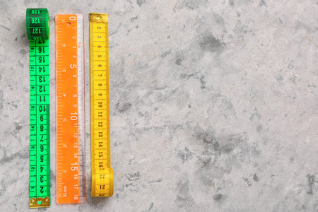Colorful measuring tapes and plastic ruler on gray grunge background