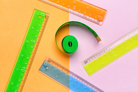 Colorful plastic rulers and measuring tape on color background