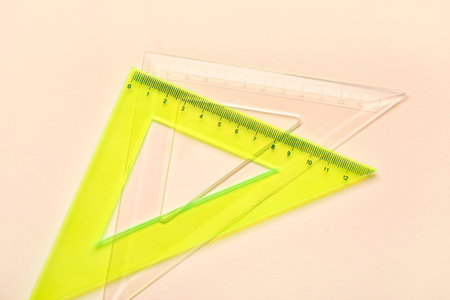 Transparent and yellow triangle plastic rulers on beige backgroundの写真素材