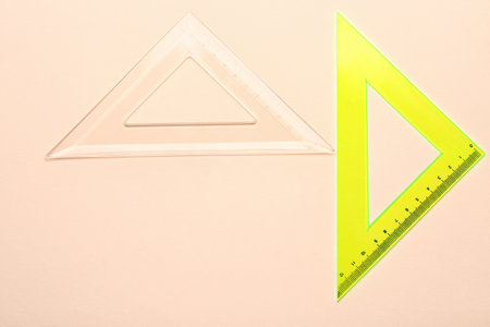 Transparent and yellow triangle plastic rulers on beige backgroundの写真素材