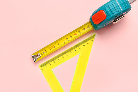Measuring tape and triangle ruler on pink backgroundの写真素材