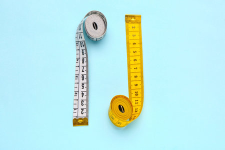 White and yellow measuring tapes on blue background
