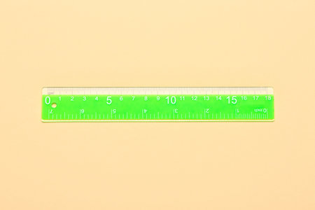 Green plastic ruler on beige backgroundの写真素材