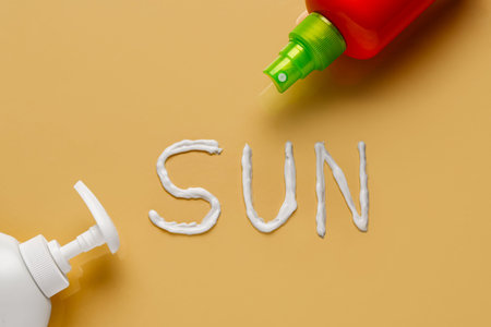 Word SUN made of sunscreen cream on yellow background