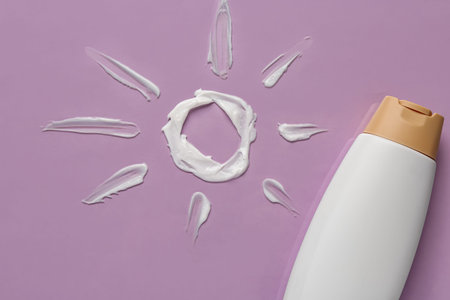 Sun made of cream with sunscreen on lilac background
