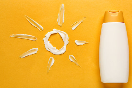 Sun made of cream with sunscreen on color background