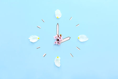 Clock made of paper and flowers on blue backgroundの写真素材