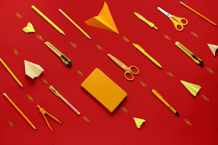 Composition with stationery supplies and paper planes on red backgroundの写真素材
