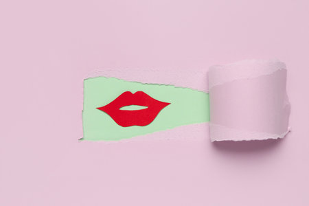 Red paper lips visible through hole in pink paperの写真素材