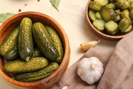 Bowl with tasty fermented cucumbers on light wooden backgroundの写真素材