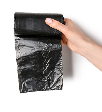 Female hand holding roll of garbage bags on white backgroundの写真素材
