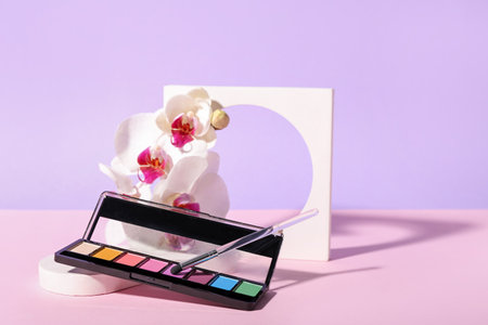 Palette of eyeshadows, brush, orchid flowers and plaster figure on lilac backgroundの写真素材