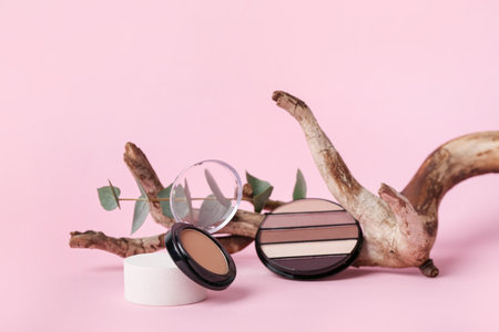 Decorative plaster podium, cosmetics and tree branch on pink backgroundの写真素材