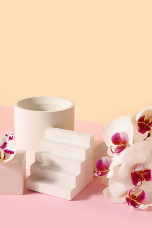 Decorative plaster podiums and beautiful orchid flowers on pink table against beige backgroundの写真素材