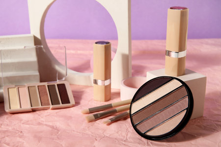 Decorative cosmetics with brushes and podiums on crumpled paper against lilac background, closeupの写真素材