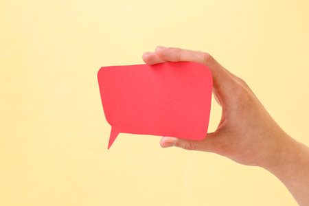 Woman holding blank speech bubble on beige backgroundの写真素材