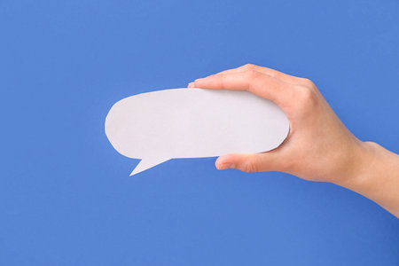 Woman holding blank speech bubble on blue backgroundの写真素材