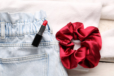 Silk scrunchy with lipstick and jeans on white wooden background, closeupの写真素材