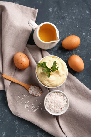 Bowl with tasty mayonnaise sauce and ingredients on green backgroundの写真素材