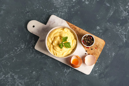 Bowl with tasty mayonnaise sauce and ingredients on green backgroundの写真素材