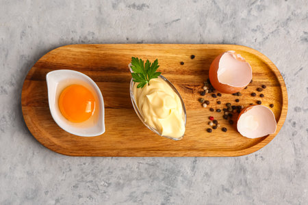 Gravy boat with tasty mayonnaise sauce and ingredients on grunge backgroundの写真素材