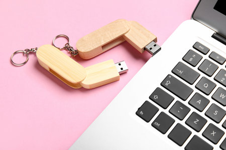 Wooden USB flash drives and modern laptop on pink backgroundの写真素材