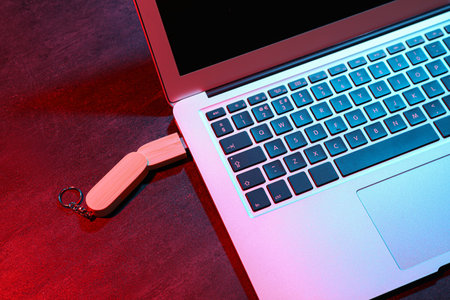 Modern laptop with wooden USB flash drive on black tableの写真素材