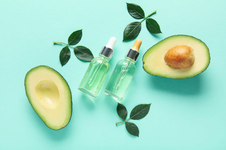 Composition with bottles of cuticle oil, avocado and plant leaves on color background
