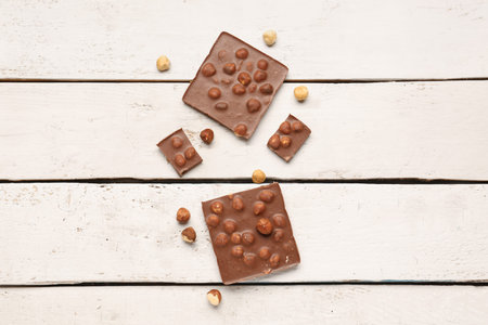 Sweet tasty chocolate with nuts on light wooden background