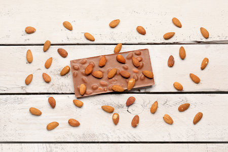 Sweet tasty chocolate with almonds on light wooden backgroundの写真素材
