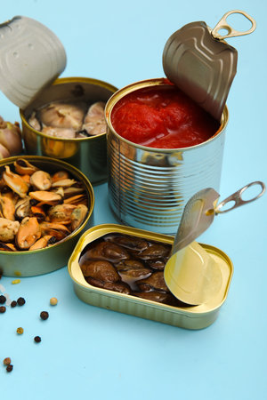 Opened tin cans with mussels and tomato sauce on blue backgroundの写真素材