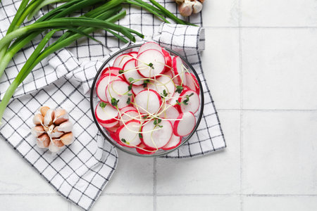 Bowl with fresh slices of radish and microgreens on light tile backgroundの写真素材