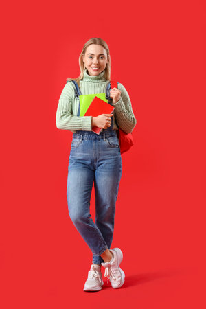 Female student with notebooks on red backgroundの写真素材