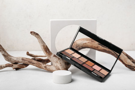 Decorative plaster podiums, palette of eyeshadows and tree branch on white tableの写真素材