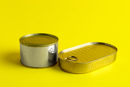 Tin cans with fish on yellow background