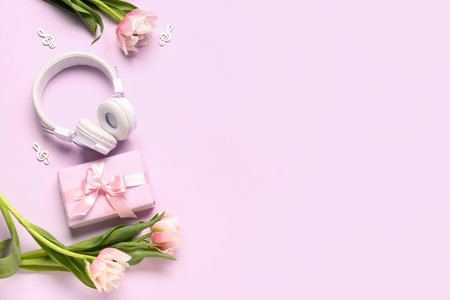 Composition with modern headphones, gift box, music notes and beautiful tulip flowers on color backgroundの写真素材
