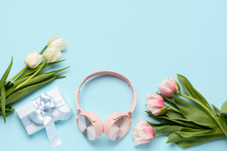 Modern headphones, beautiful tulip flowers and gift box on color backgroundの写真素材