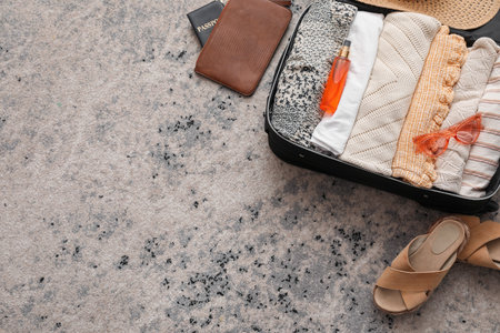 Suitcase with summer clothes and accessories on color carpet