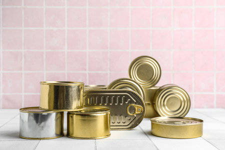 Tin cans with fish on white tiled table