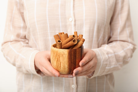 Woman with bowl of cinnamon sticks on white background, closeupの写真素材