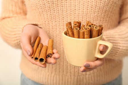 Woman with cup and cinnamon sticks on white background, closeupの写真素材