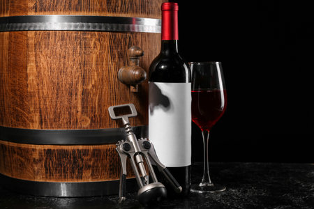 Wooden barrel, corkscrew, bottle and glass of wine on dark backgroundの写真素材