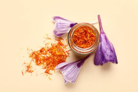 Jar of dried saffron threads and crocus flowers on beige backgroundの素材 [FY310203159734]