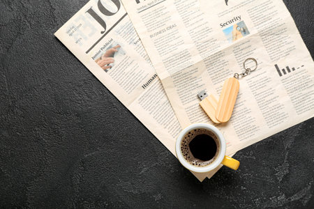 Newspapers with USB flash drive and cup of coffee on dark backgroundの写真素材