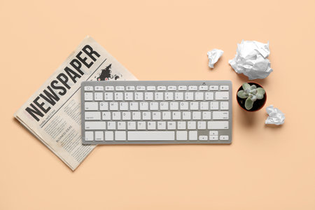 Computer keyboard with newspaper and flowerpot on beige backgroundの写真素材