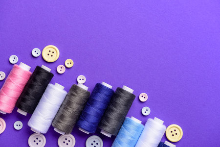 Composition with different thread spools and buttons on color background